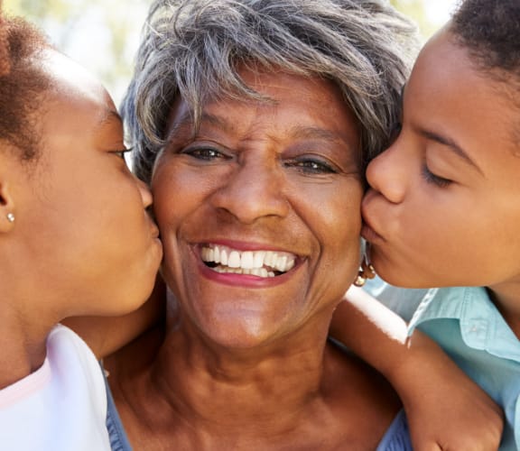 Two grandchildren kissing their grandmother on the cheeks