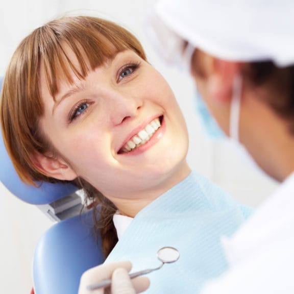 Woman in dental chair having her teeth looked at